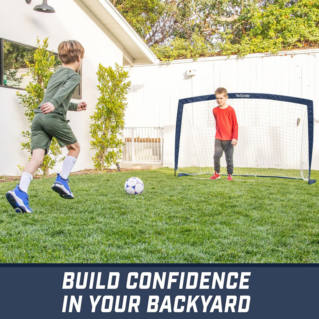 a boy kicking a soccer ball in the yard