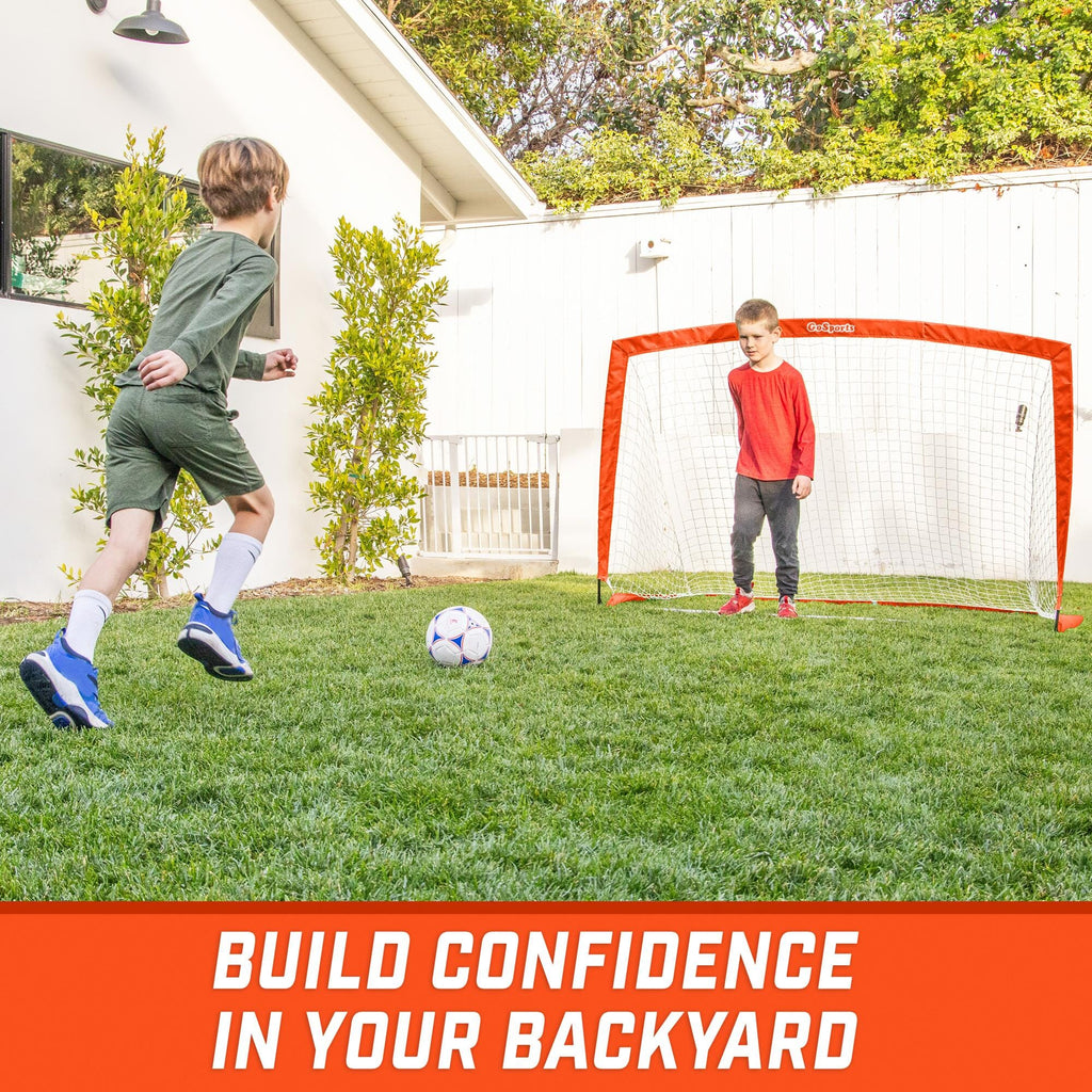 a boy kicking a soccer ball in the yard